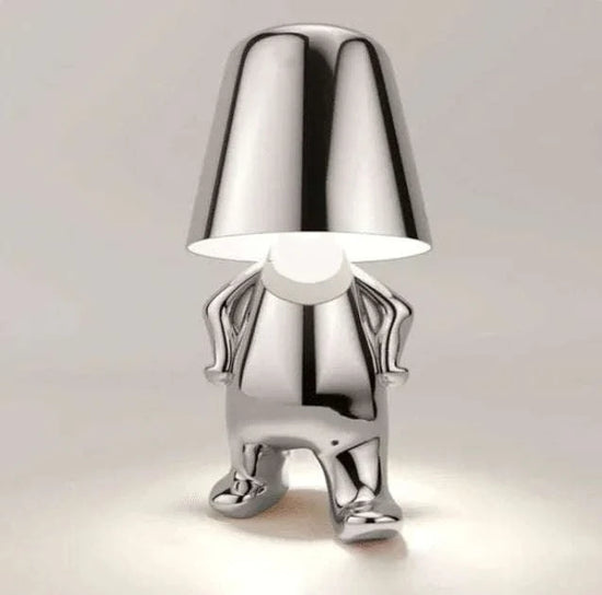 Impression LED Lamp in shiny silver metal with a humanoid figure base holding a large lampshade, modern and playful design.