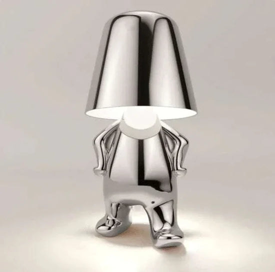 Impression LED Lamp with chrome finish shaped like a playful standing figure holding its lampshade hands on hips, modern design