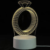3D LED Lamp shaped like a wireframe diamond ring emitting soft yellow light on a white circular base