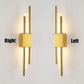 Modern LED wall lamp with sleek iron and acrylic design in gold, emitting warm white light.