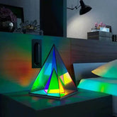 Aura Pyramid Lamp with multicolored translucent acrylic panels creating a vibrant ambient glow on a bedside table
