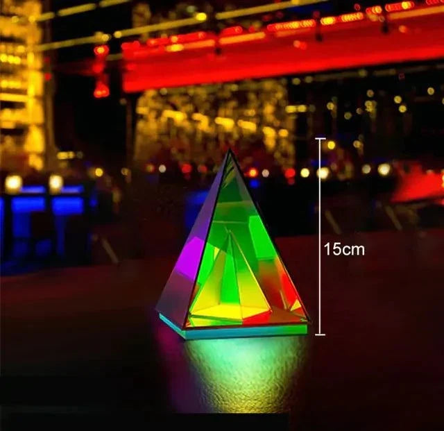 Aura Pyramid Lamp glowing with vibrant multicolored light inside a transparent pyramid-shaped acrylic structure on a table