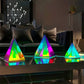 Aura Pyramid Lamp set with three pyramid-shaped acrylic lamps in vibrant rainbow colors on a reflective surface
