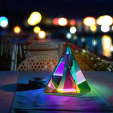 Aura Pyramid Lamp emitting vibrant rainbow-colored ambient light with a translucent pyramid design on a table
