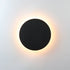 Circular Wall Light with a sleek black circular metal design and warm white backlighting creating a glowing halo effect.