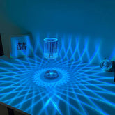 Cristal Lamp with clear faceted glass surface emitting intricate blue light patterns creating a shimmering effect on the table