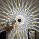 Cristal Lamp with clear faceted glass body casting intricate geometric light patterns on wall when illuminated