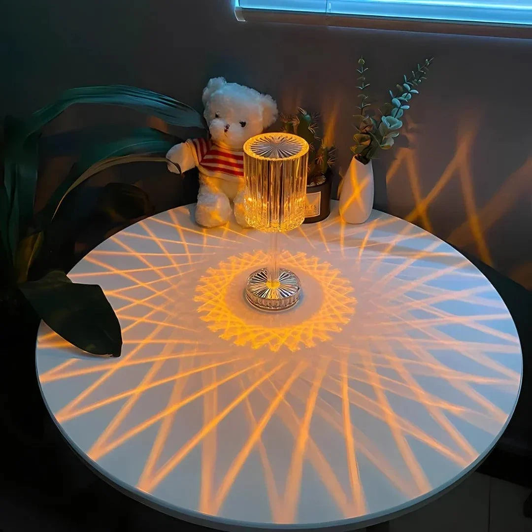 Cristal Lamp with clear faceted glass casting intricate warm geometric light patterns on a white round table