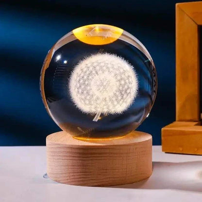 Crystal Night Ball glass sphere with a glowing white dandelion design on a natural wood base