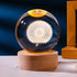 Crystal Night Ball glass sphere with a glowing white dandelion design on a natural wood base