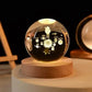 Crystal Night Ball, clear glass globe with engraved solar system design on a natural wood base

