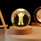 Crystal Night Ball glass globe with a glowing astronaut figure, set on a natural wood base with a round design