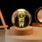 Crystal Night Ball featuring a clear glass globe with bear figurine and warm light on a round wooden base