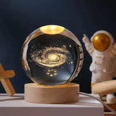 Crystal Night Ball, transparent glass sphere with glowing galaxy pattern on a natural wood base
