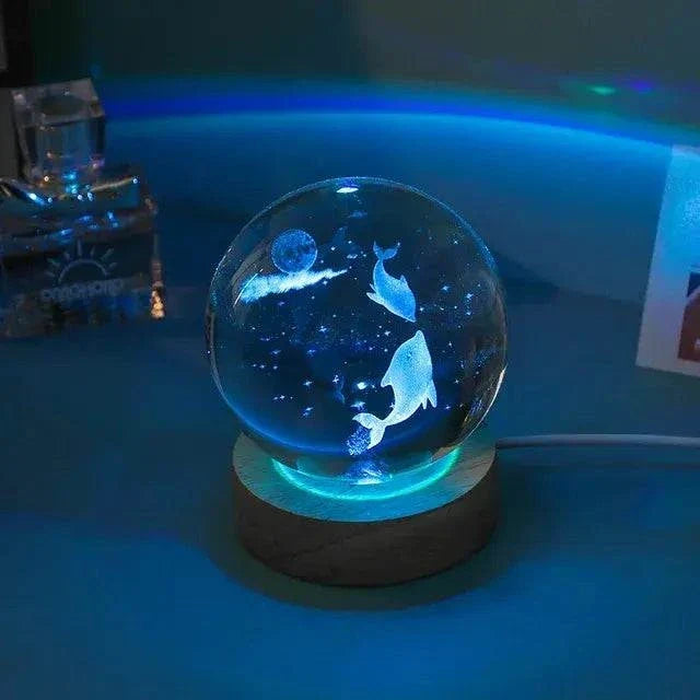 Crystal Night Ball with glowing glass sphere, dolphin pattern and dark wooden base for ambient lighting