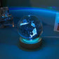 Crystal Night Ball with glowing glass sphere, dolphin pattern and dark wooden base for ambient lighting