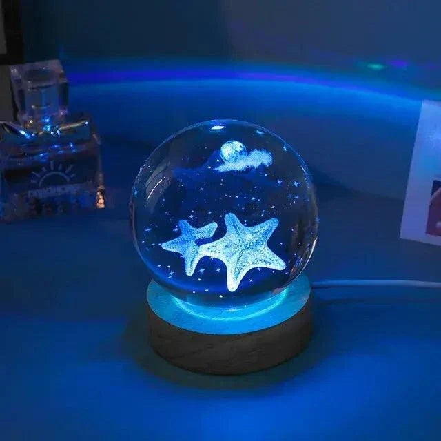Crystal Night Ball with clear glass globe, glowing blue starfish design, and round dark wood base for ambient lighting