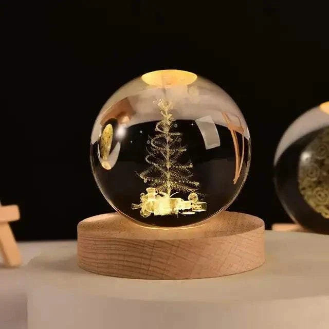 Crystal Night Ball, clear glass sphere with engraved golden tree and reindeer, on a natural wood base