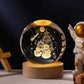 Crystal Night Ball, a clear glass sphere with glowing snowmen and stars on a natural wood base