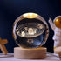 Crystal Night Ball, transparent glass globe with engraved solar system design on a natural wood base
