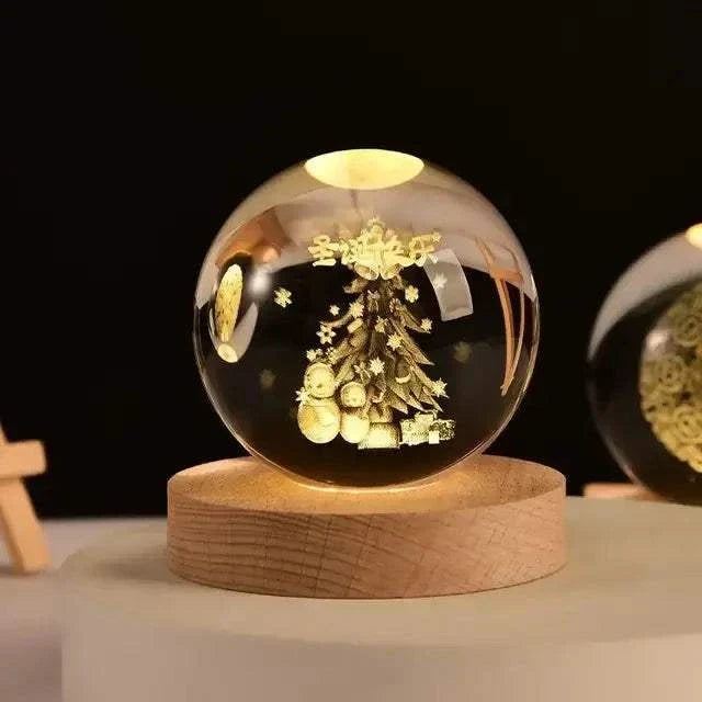 Crystal Night Ball, clear glass sphere with engraved golden Christmas tree scene on a natural wood base