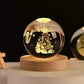 Crystal Night Ball, clear glass sphere with engraved golden Christmas tree scene on a natural wood base