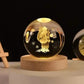 Crystal Night Ball, clear glass sphere with etched teddy bear and snowflakes on a natural wood base