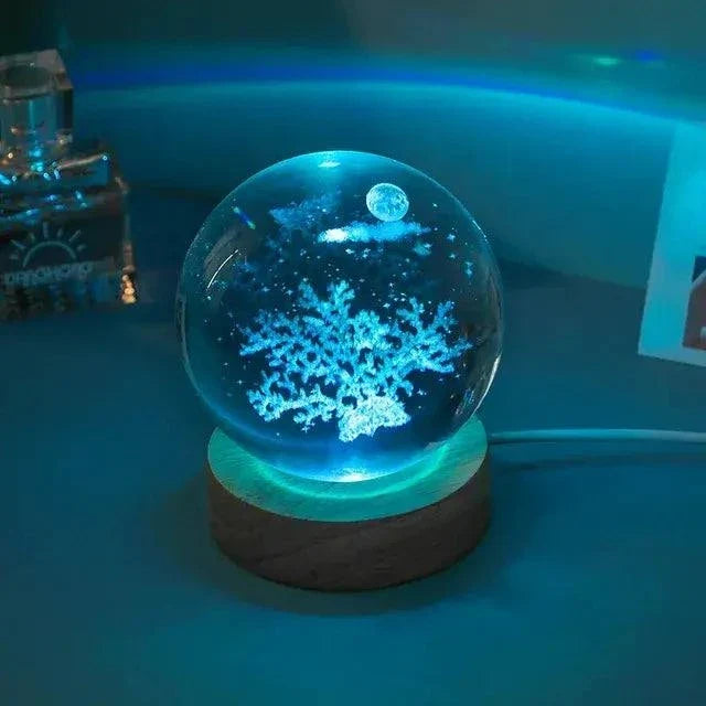 Crystal Night Ball, blue glass globe with glowing snowflake pattern on a dark wooden base
