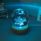 Crystal Night Ball, blue glass globe with glowing snowflake pattern on a dark wooden base
