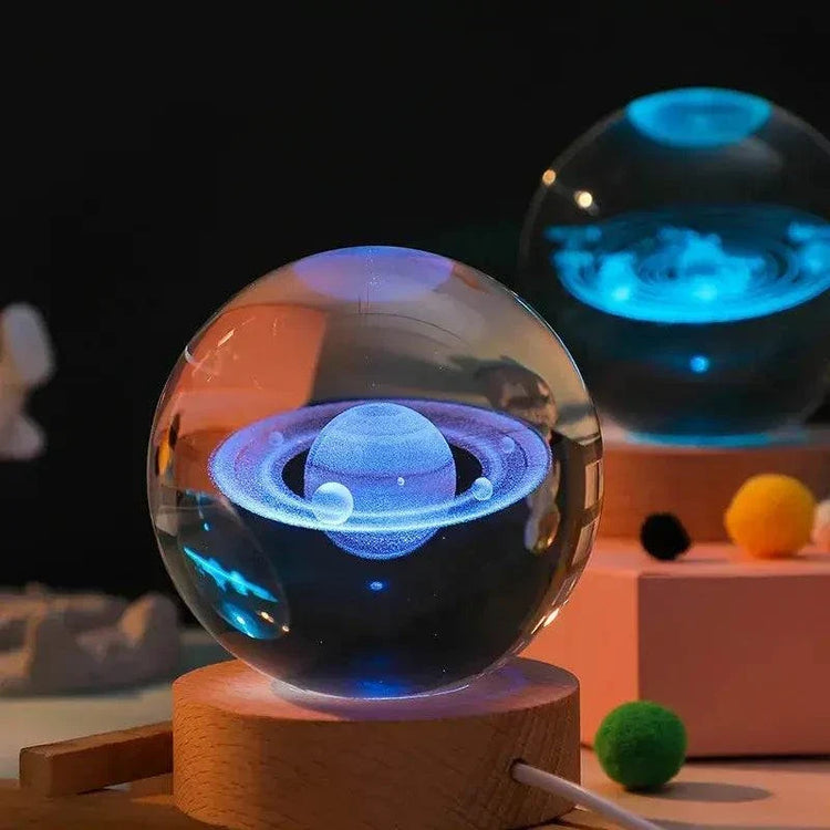Crystal Night Ball glass orb with colorful planet design, displayed on a natural wood base with ambient light