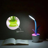 Flower Lamp with flexible blue stem, white flowerpot base, pink rim, and soft LED light illuminating an open book