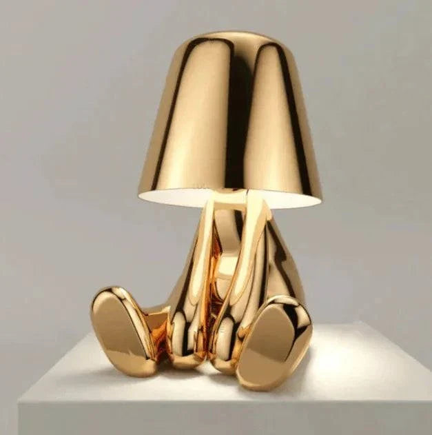 Impression LED Lamp with a shiny gold metallic finish in a playful sitting figure design with a conical lampshade