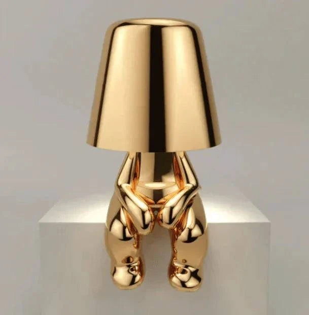 Impression LED Lamp with shiny gold metallic finish shaped like a sitting figure holding the lampshade, sleek and modern design