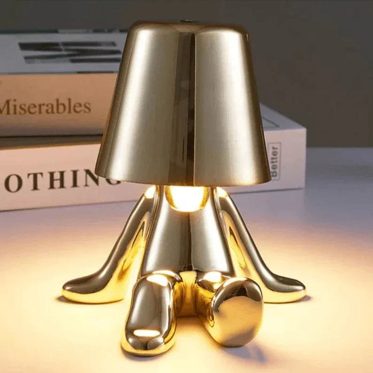 Impression LED Lamp with a shiny gold metallic finish and unique abstract feet design illuminating warm light