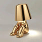 Impression LED Lamp in shiny gold finish shaped like a sitting figure with a lampshade for the head emitting a soft white light
