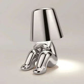 Impression LED Lamp in shiny silver metallic finish with a modern figure design sitting under a lampshade emitting soft light