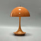 Portable rechargeable LED lamp with metal lampshade and USB charging on wooden table