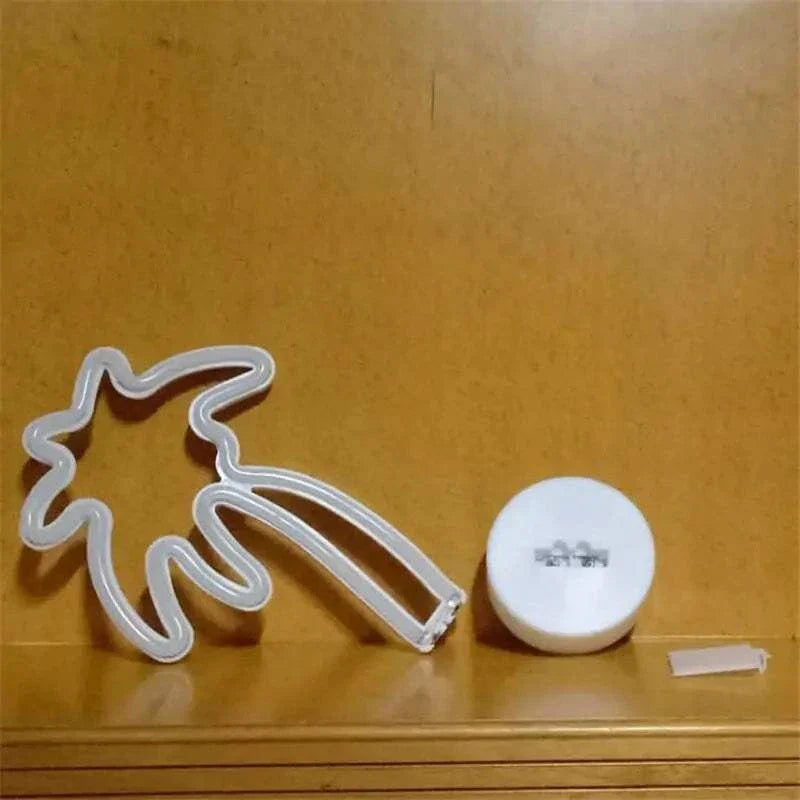 LED Neon Light shaped as a palm tree with white PVC tubing and a round white battery compartment on a wooden surface