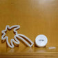 LED Neon Light shaped as a palm tree with white PVC tubing and a round white battery compartment on a wooden surface