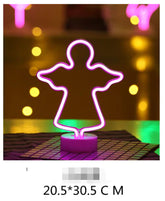 LED Neon Light shaped like an angel in glowing pink mounted on a white circular base with a grid pattern underneath