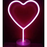 LED Neon Light in bright pink PVC shaped like a heart with a clear round base, glowing vibrantly in the dark