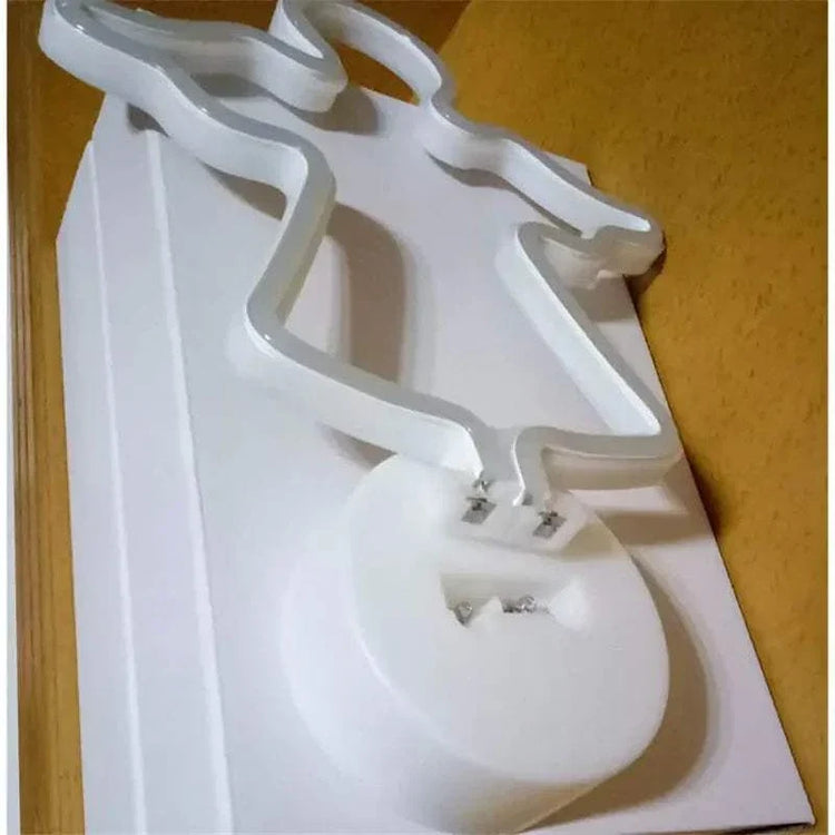 White LED Neon Light in the shape of a reindeer with clear plastic base and battery compartment visible, unlit