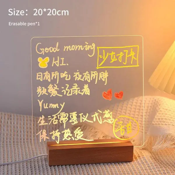 LED Note Board with clear acrylic surface and warm yellow illuminated handwritten messages, resting on a wooden base