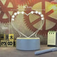 LED Note Board with a heart-shaped luminous acrylic panel decorated with floral patterns on a white base, emitting warm white light