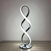 LED Table Lamp with silver chrome finish and modern twisted infinity loop design emitting bright white light