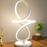 LED Table Lamp with modern white LED light in a looping figure-eight design on a round base emitting ambient glow