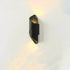 LED Waterproof Outdoor Wall Lamp in black metal with a twisted cylindrical shape and warm light glowing from top and bottom