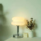 Macaron LED Lamp with a glossy white rounded shade, chrome metal stem and circular base, emitting warm light
