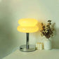 Macaron LED Lamp with a glossy yellow double-disc shade, chrome metal stem, and round reflective base