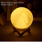 Moon Lamp emitting warm yellow light with detailed lunar surface on a natural wooden stand in dark setting